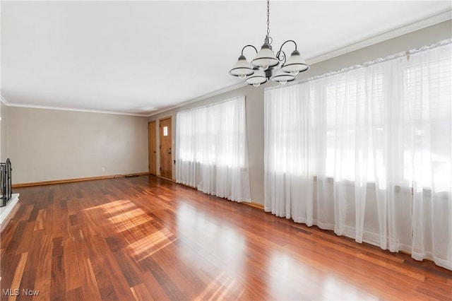 unfurnished living room with dark hardwood / wood-style floors, crown molding, and a chandelier