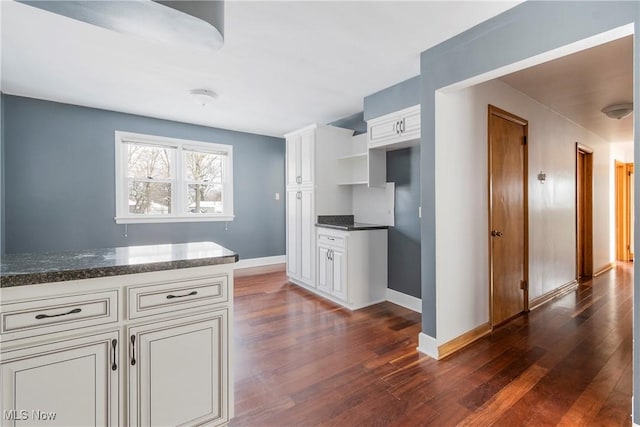 kitchen with white cabinetry, dark hardwood / wood-style flooring, and dark stone counters