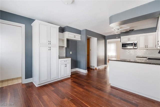 kitchen with tasteful backsplash, dark stone counters, and white cabinetry