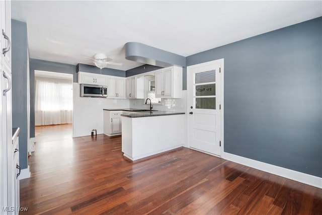 kitchen featuring white cabinetry, decorative backsplash, sink, dark hardwood / wood-style floors, and kitchen peninsula