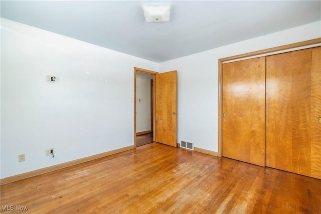 unfurnished bedroom featuring a closet and hardwood / wood-style flooring