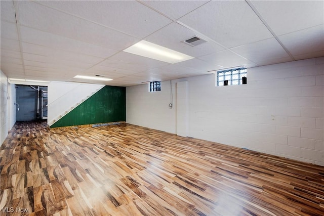 basement with a drop ceiling and hardwood / wood-style flooring