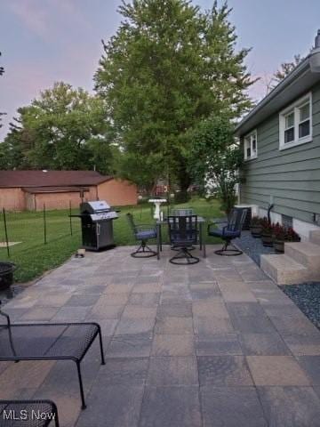 patio terrace at dusk with a grill and a yard