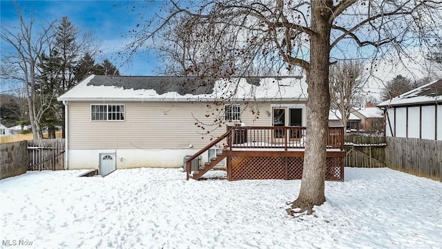 snow covered back of property with a wooden deck