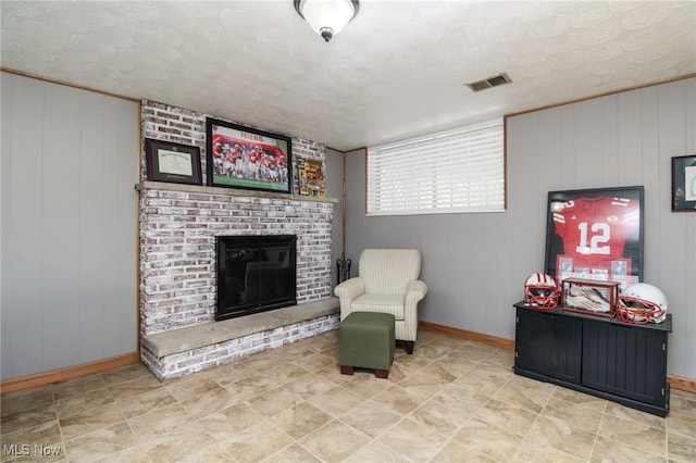 sitting room with a brick fireplace, wood walls, and a textured ceiling