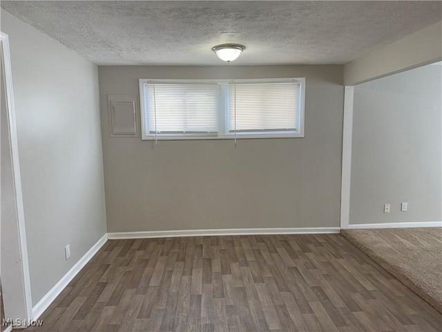 spare room with a textured ceiling and dark wood-type flooring