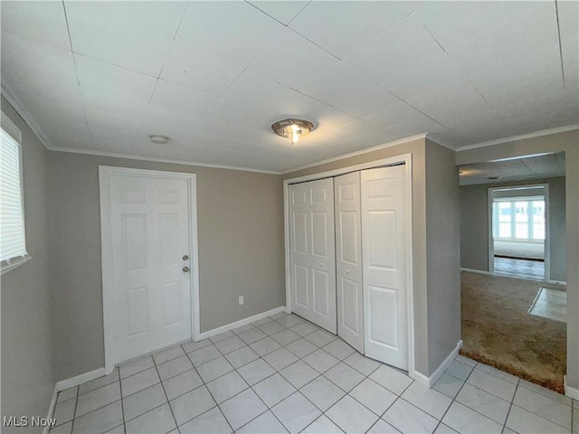 unfurnished bedroom with a closet, crown molding, and light colored carpet