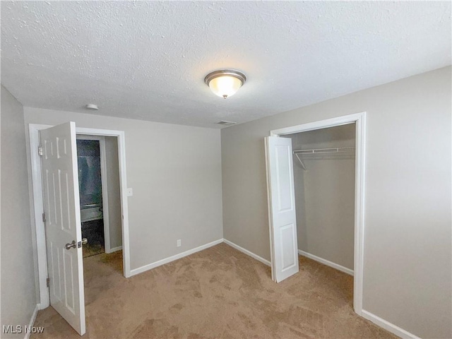 unfurnished bedroom featuring light carpet, a closet, and a textured ceiling