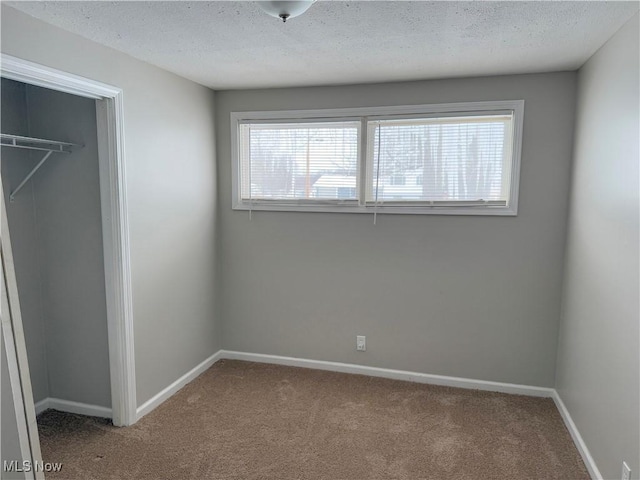 unfurnished bedroom with a textured ceiling, a closet, and carpet