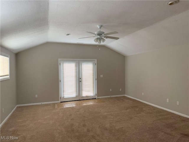 bonus room with a textured ceiling, lofted ceiling, light carpet, french doors, and ceiling fan