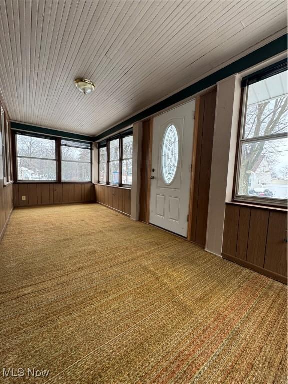 unfurnished sunroom featuring wood ceiling and plenty of natural light