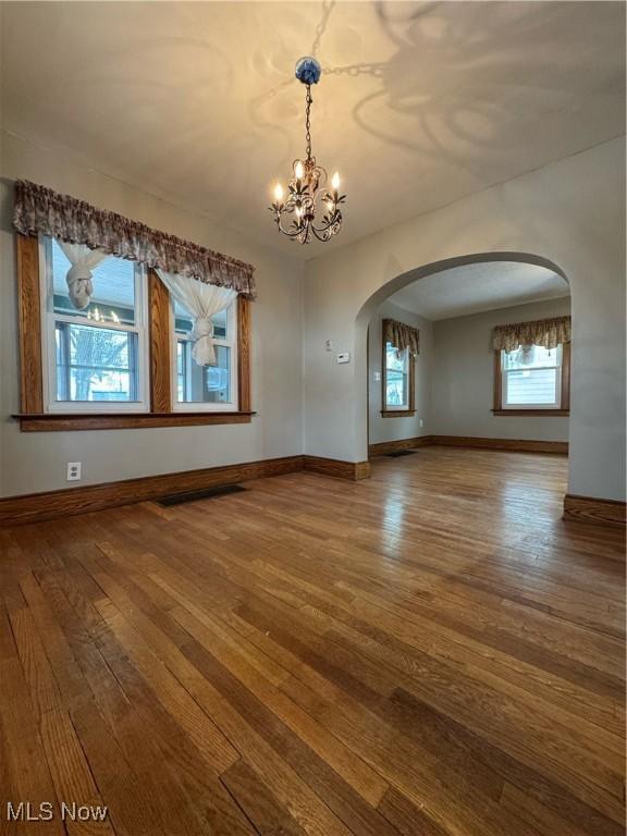 unfurnished dining area featuring a chandelier and hardwood / wood-style flooring