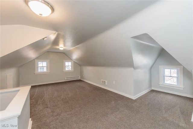 bonus room with vaulted ceiling, baseboard heating, a healthy amount of sunlight, and dark colored carpet