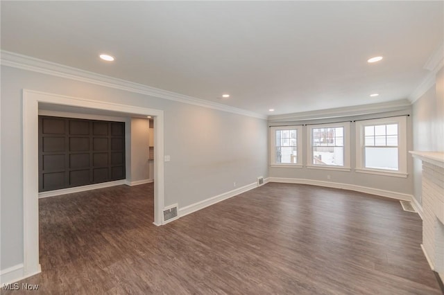 spare room featuring dark wood-type flooring, ornamental molding, and a brick fireplace