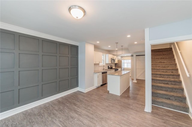 kitchen featuring white cabinetry, appliances with stainless steel finishes, decorative light fixtures, light stone countertops, and a center island