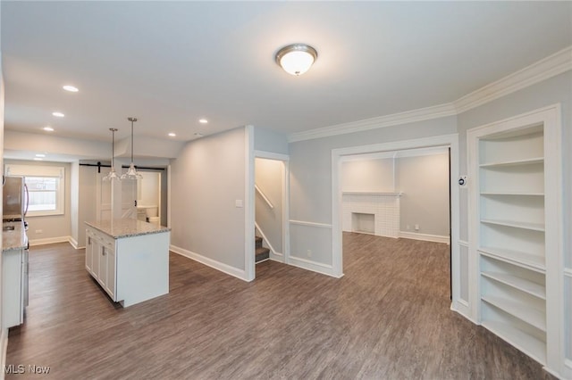 kitchen with light stone countertops, pendant lighting, a center island, dark wood-type flooring, and white cabinetry