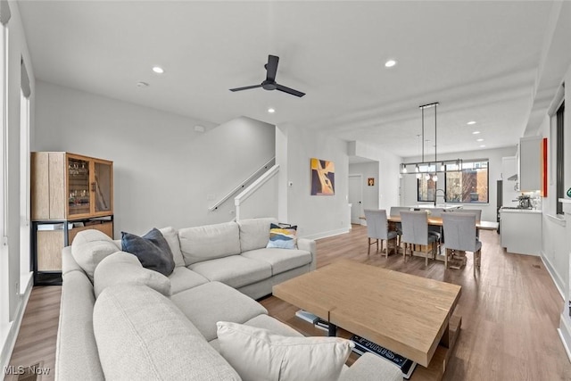 living room featuring light wood-type flooring, sink, and ceiling fan