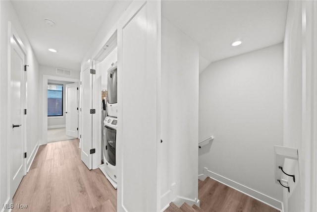 hall with stacked washer / dryer, vaulted ceiling, and light wood-type flooring