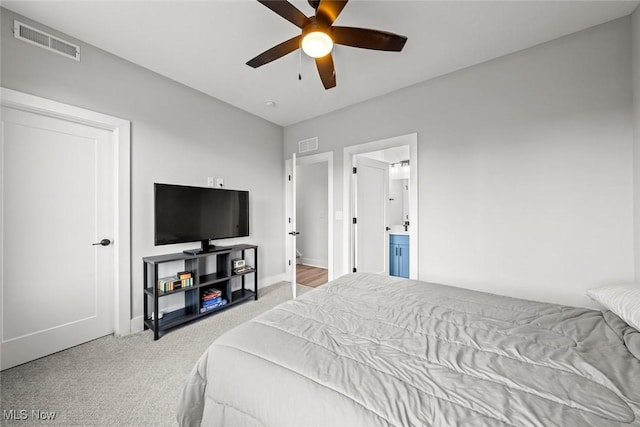 bedroom featuring ceiling fan, ensuite bathroom, and light colored carpet