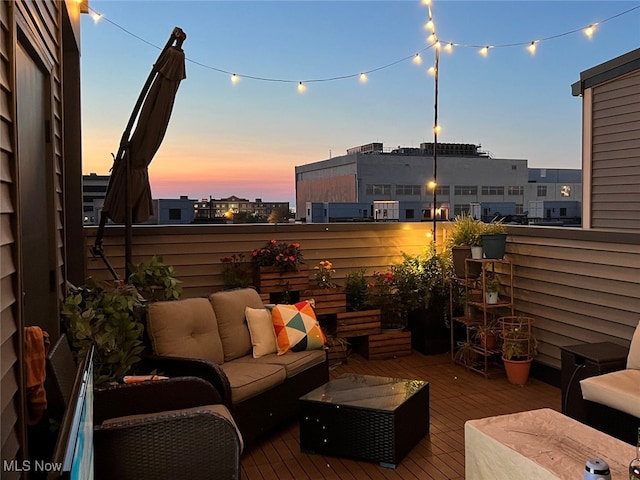 patio terrace at dusk with outdoor lounge area and a balcony