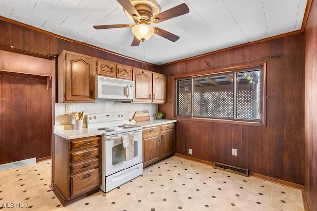 kitchen featuring ceiling fan, wood walls, and white appliances