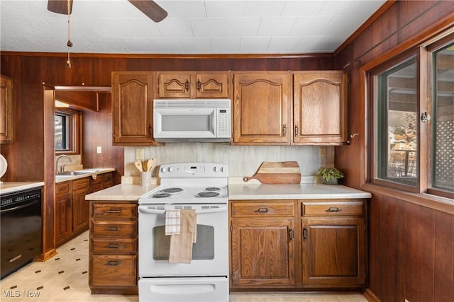 kitchen with ceiling fan, wooden walls, sink, and white appliances