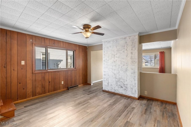 spare room with ceiling fan, ornamental molding, and wooden walls