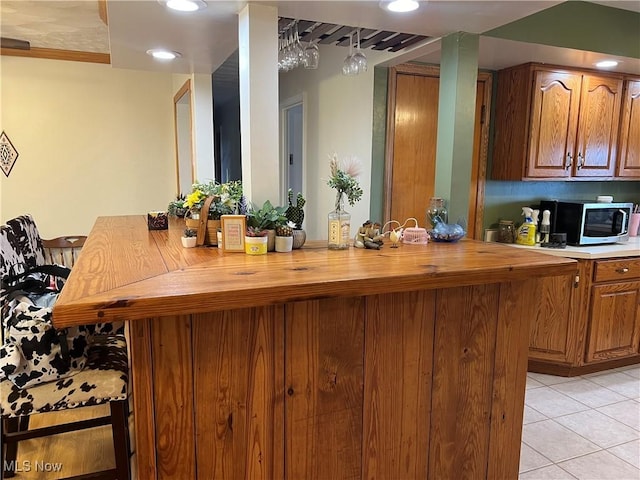 kitchen with light tile patterned floors, kitchen peninsula, and a breakfast bar area