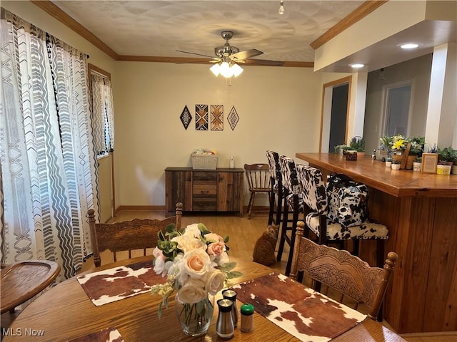 dining area with ceiling fan, crown molding, and light hardwood / wood-style flooring