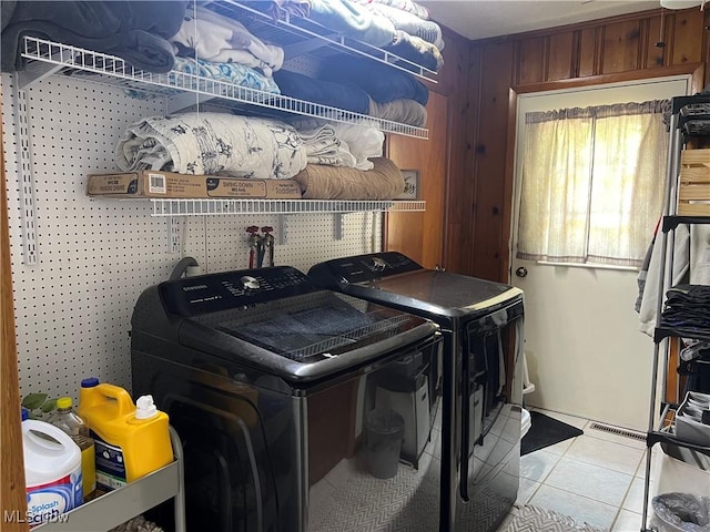 laundry room featuring light tile patterned floors, washing machine and dryer, and wood walls