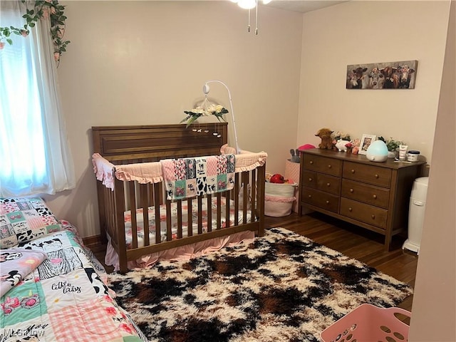 bedroom with a nursery area and dark hardwood / wood-style flooring