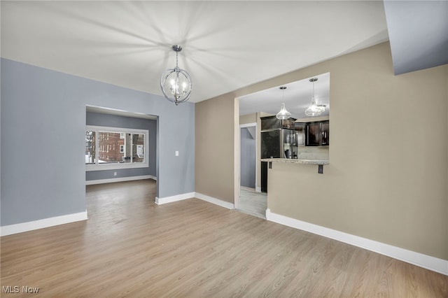 unfurnished living room with light wood-type flooring and a notable chandelier