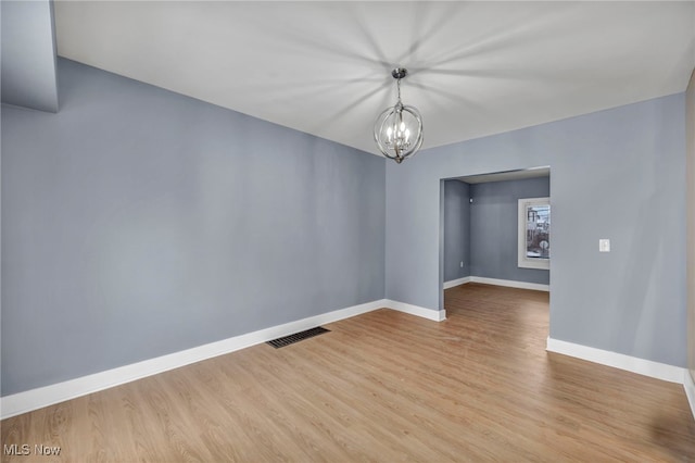 empty room with light hardwood / wood-style flooring and a notable chandelier