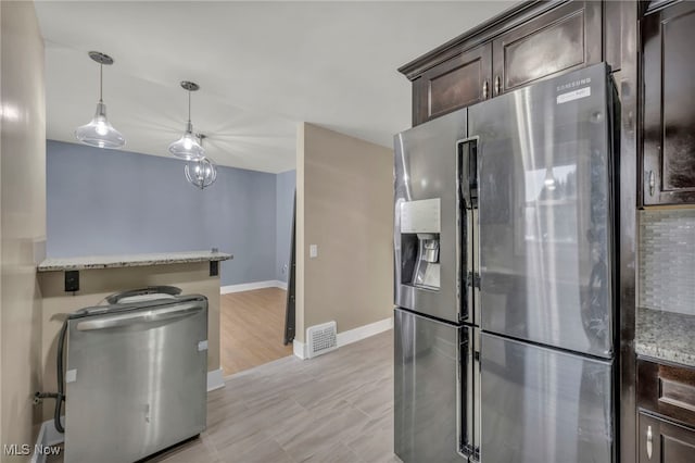 kitchen with stainless steel refrigerator with ice dispenser, light stone counters, dark brown cabinetry, and decorative light fixtures