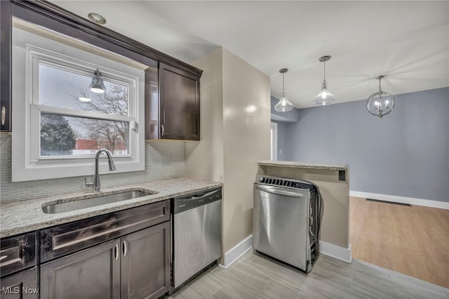 kitchen featuring dishwasher, sink, light stone counters, and dark brown cabinetry