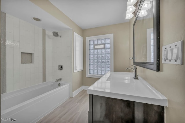 bathroom with tiled shower / bath combo, vanity, and a notable chandelier