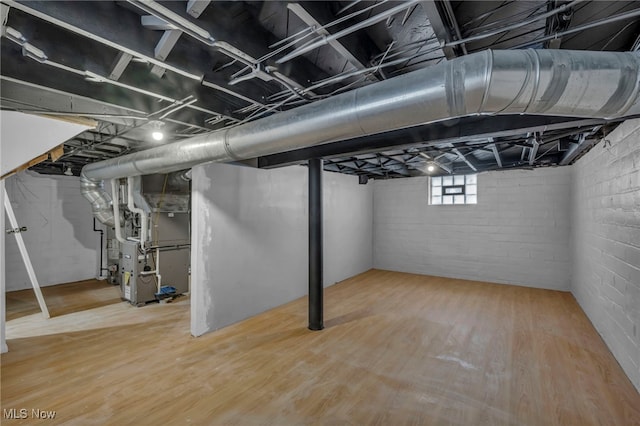 basement with heating unit and hardwood / wood-style flooring