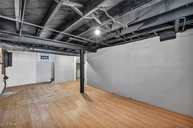 basement with electric panel and hardwood / wood-style flooring