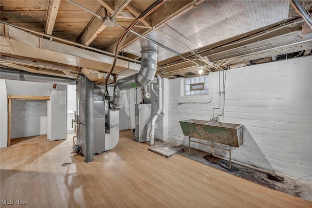 basement with light hardwood / wood-style floors, sink, electric water heater, and heating unit