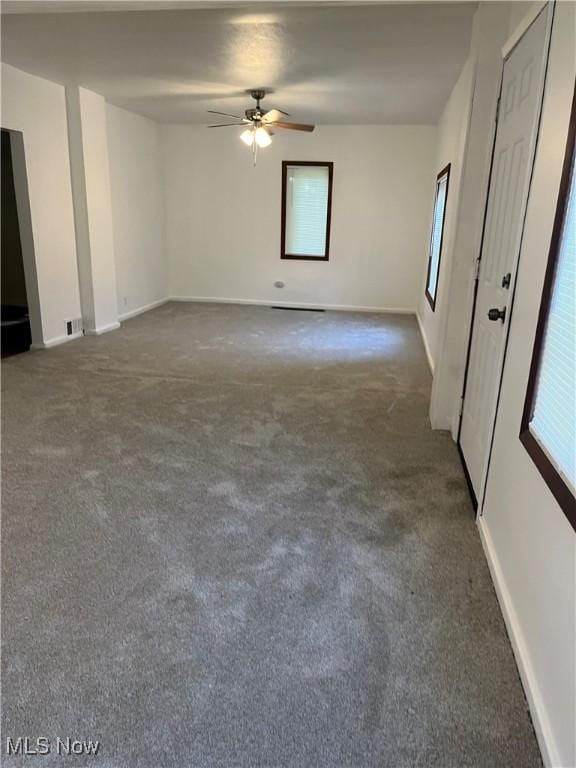 empty room featuring ceiling fan and dark colored carpet