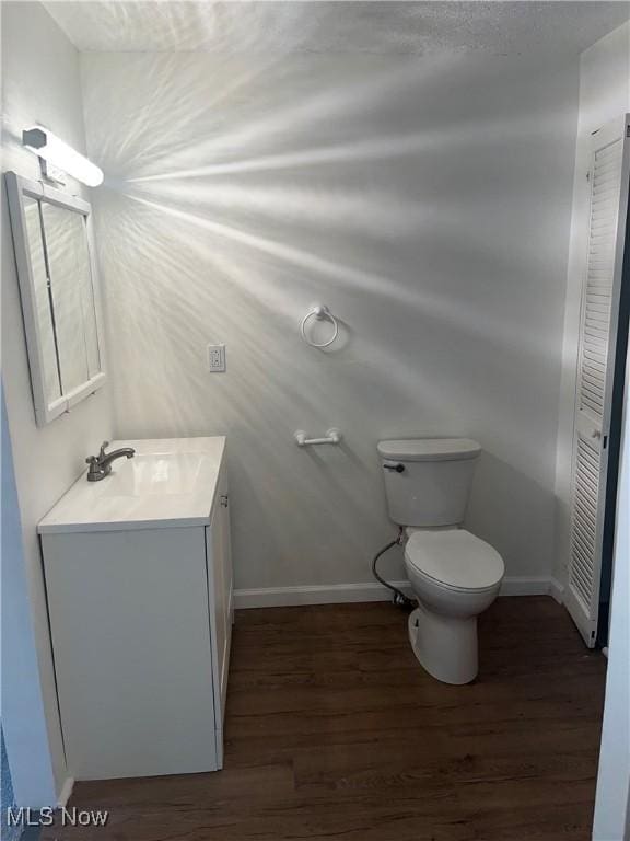 bathroom featuring toilet, hardwood / wood-style flooring, and vanity