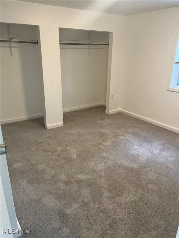 unfurnished bedroom featuring dark carpet and a wall mounted AC