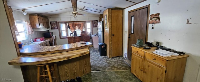 kitchen featuring ceiling fan, a wealth of natural light, dark colored carpet, and vaulted ceiling