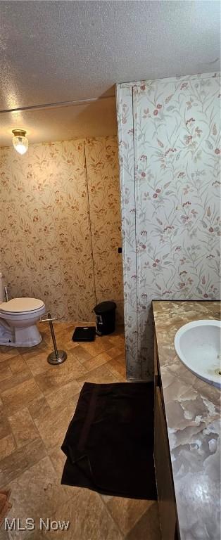 bathroom featuring a textured ceiling, toilet, and vanity