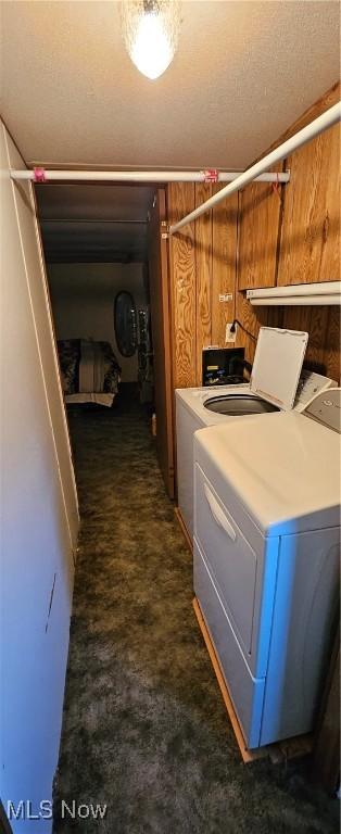 laundry room with dark colored carpet, independent washer and dryer, and wooden walls