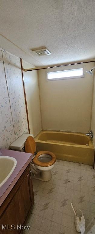 full bathroom with toilet, a wealth of natural light, a textured ceiling, and vanity