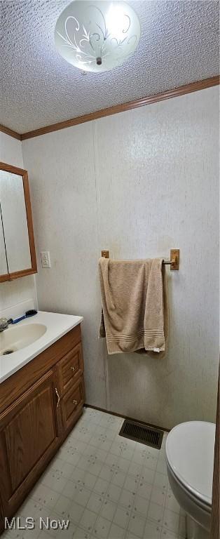 bathroom with toilet, vanity, and ornamental molding