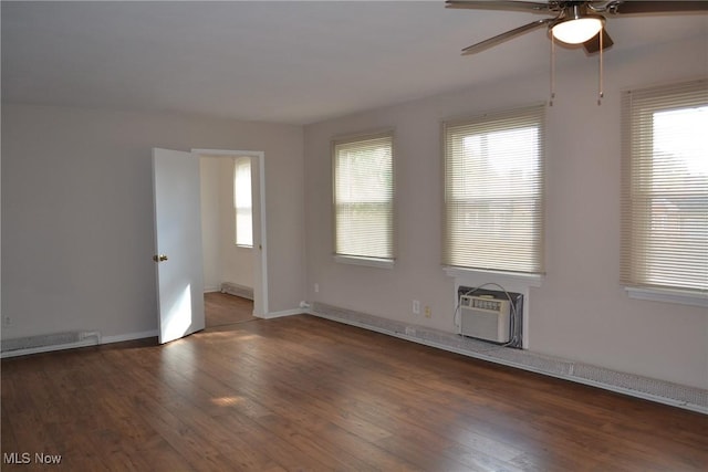 spare room featuring ceiling fan, a wealth of natural light, dark hardwood / wood-style floors, and an AC wall unit