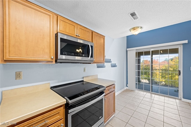 kitchen featuring a textured ceiling, stainless steel appliances, and light tile patterned flooring