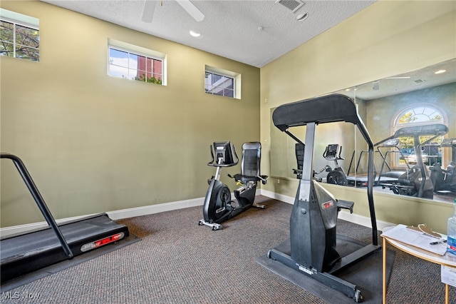 exercise area with a textured ceiling, ceiling fan, and carpet flooring